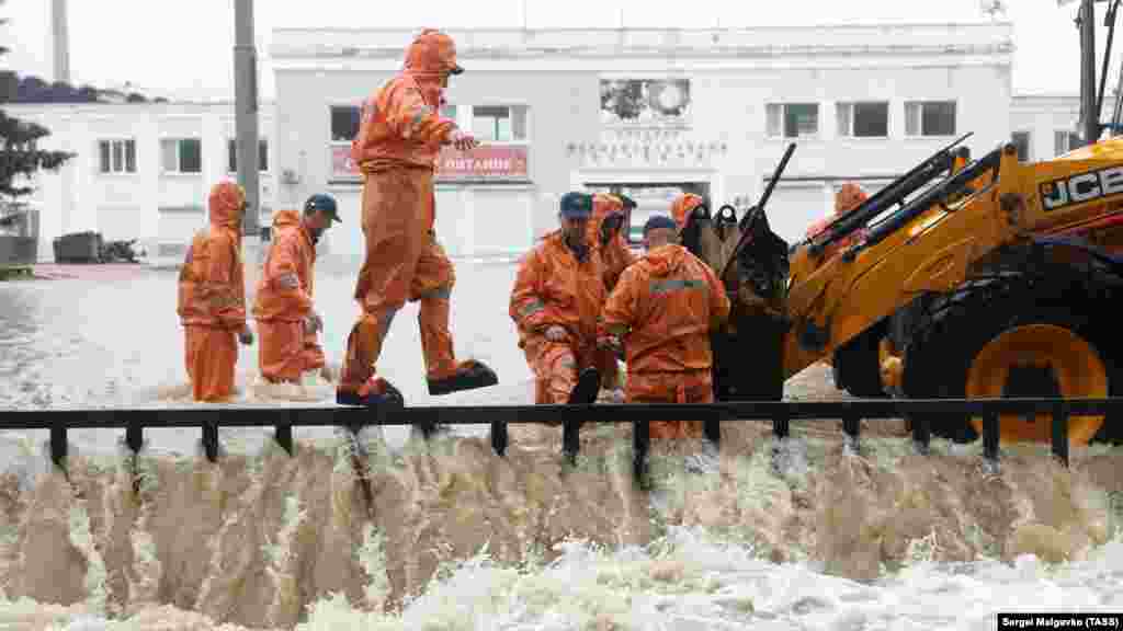 Сотрудники российского МЧС освобождают путь для стока воды в речку Мелек-Чесме на улице Маршала Еременко перед стадионом имени 50-летия Октября