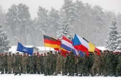 Военнослужащие НАТО с флагами своих стран и флагом Альянса во время учений в Литве, февраль 2019 года